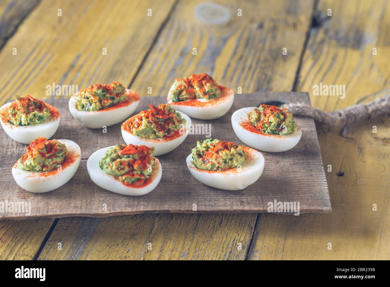 Guacamole and bacon deviled eggs on cutting board Stock Photo