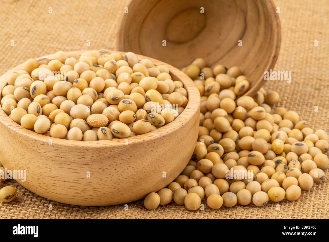 Soy beans in a wooden bowl with a  pile of soy beans on sackcloth Stock Photo