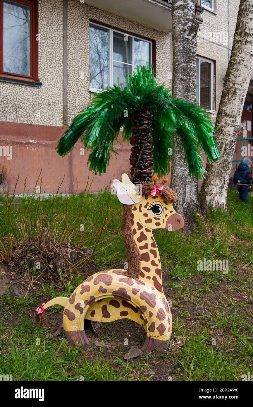 Decor garden in the courtyard of an apartment building in a provincial city  - giraffe from car tires and plywood and palm tree from plastic bottles.  Spring Stock Photo - Alamy, image size:865x1390