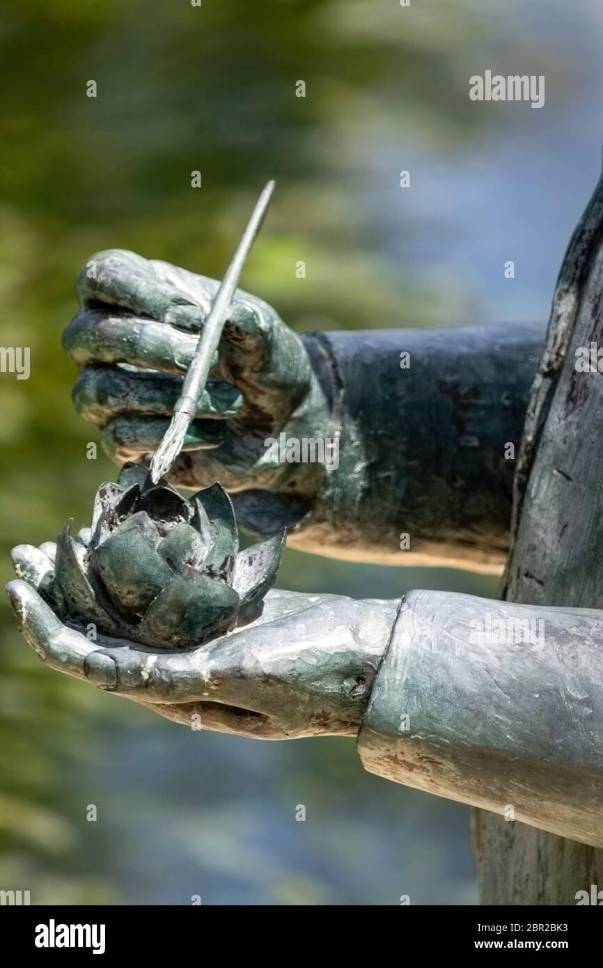 part of a statue of hands holding water lily and paint brush dusting