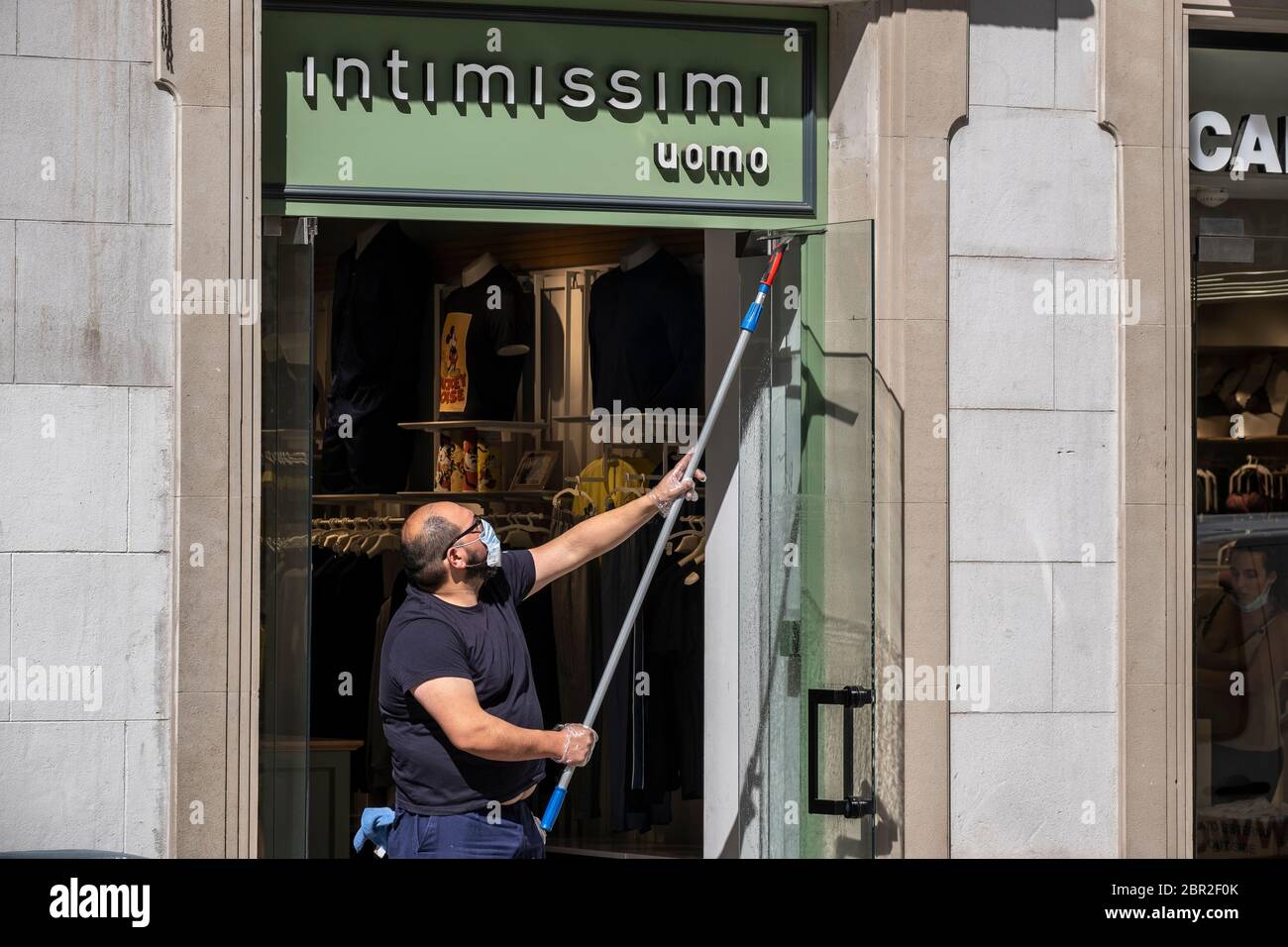 A man from Intimissimi's private cleaning service is seen cleaning a shop  window.The small and medium-sized retail business in Barcelona prepare to  manage sales during the Phase 1 of the Covid-19 pandemic