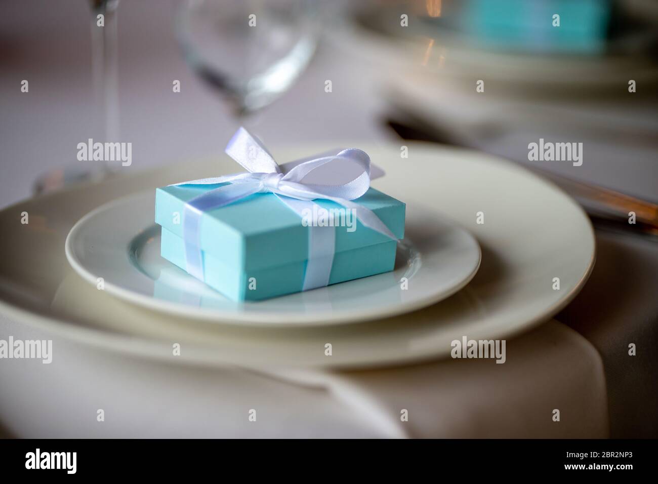 Festive table setting with handmade gift box on plate. Light blue ...