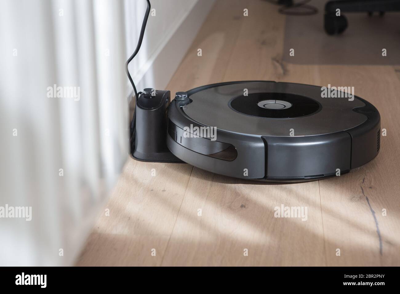 robot vacuum cleaner charging in the charging base. Wood floor and