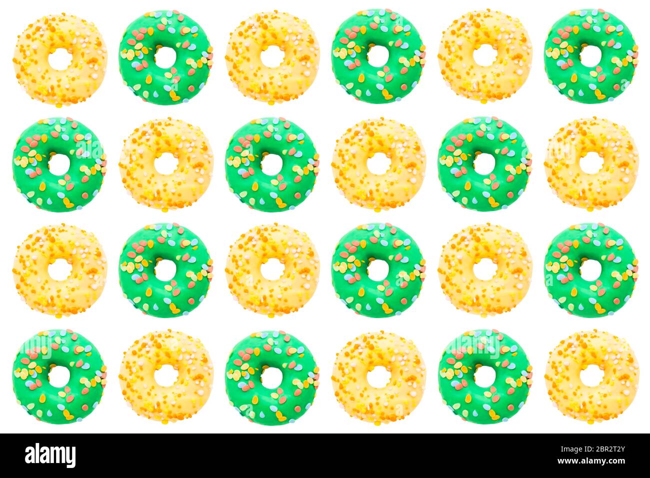 Pattern of green and yellow donuts on a white background. Flat lay ...