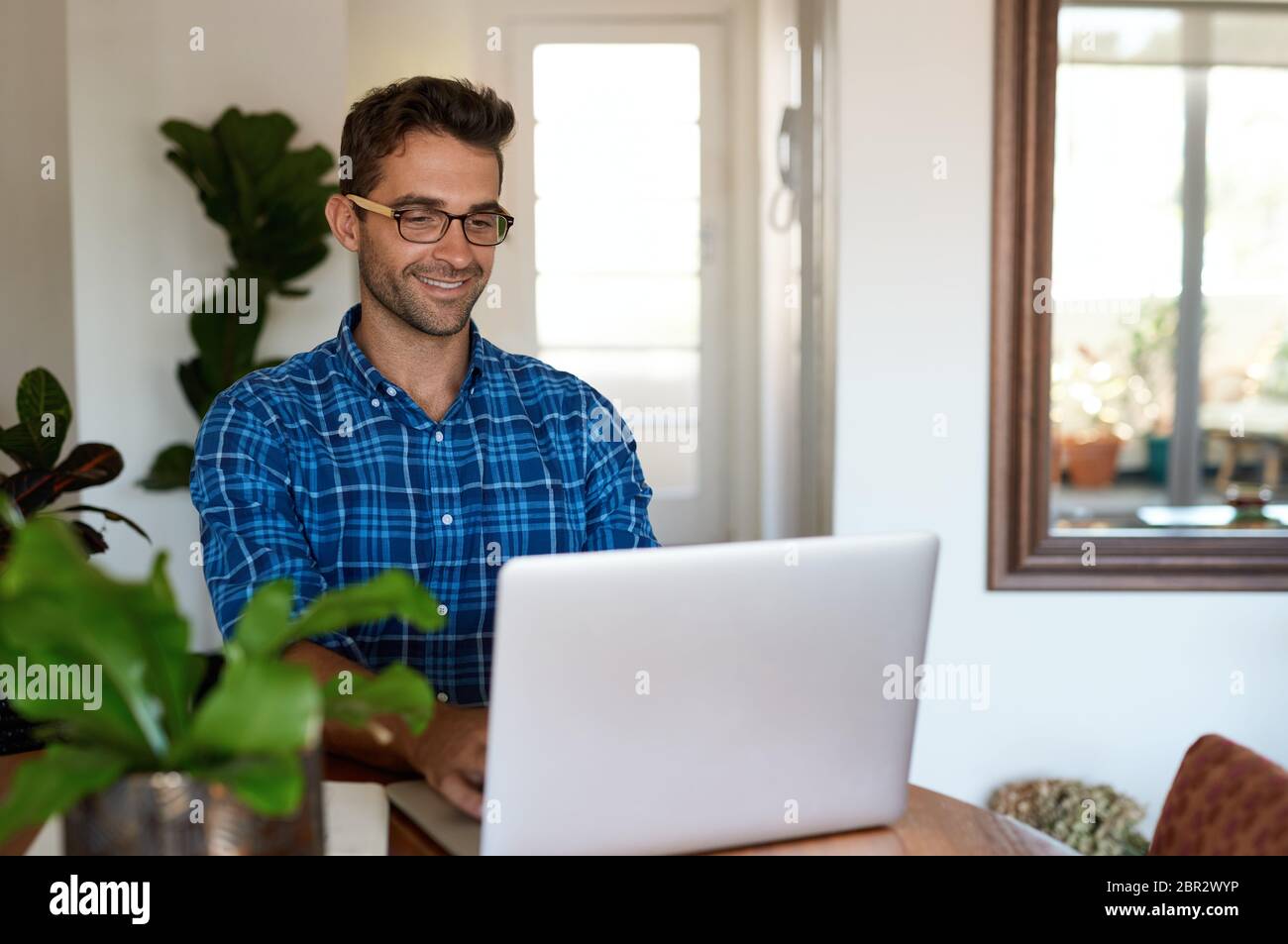 Smiling man working from home with a laptop Stock Photo