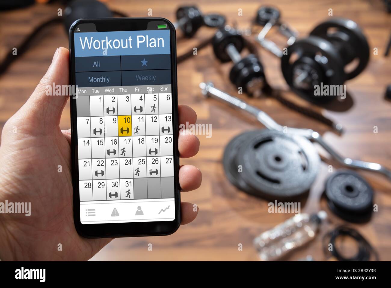 Close up Of A Person Hand Holding Workout Plan Calendar On Smartphone close-up-of-a-person-hand-holding-workout-plan-calendar-on-smartphone