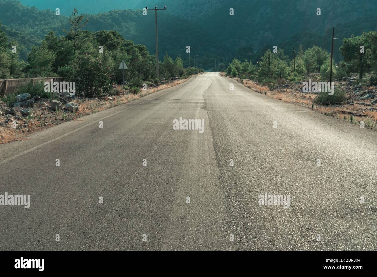 Empty rural countryside tarmac road outside Antalya With green trees along the way and maountains in the background. Stock Photo