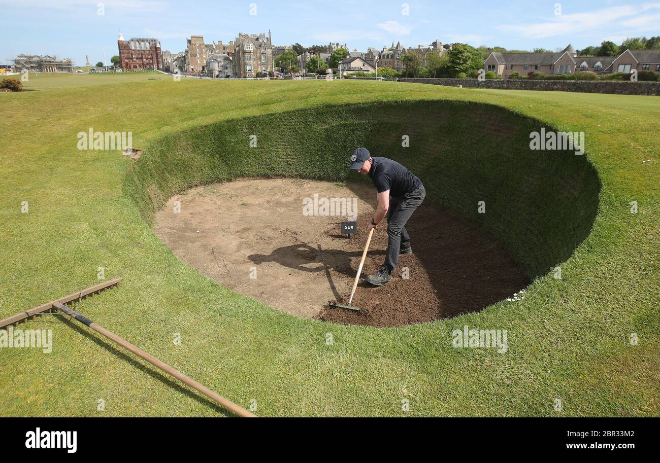 Director of Green Keeping at St Andrews Links Trust Sandy Reid rakes the Road Hole bunker at the 17th green on the Old Course at St Andrews. First Minister Nicola Sturgeon is due to announce a 'route map' for lifting the coronavirus lockdown in Scotland on Thursday Stock Photo