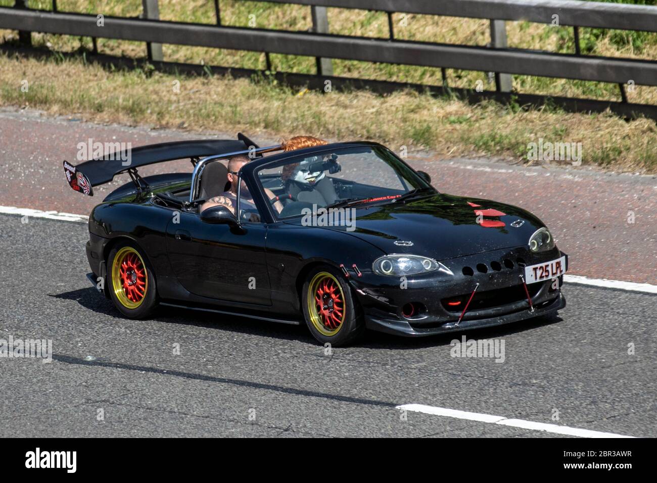 2013 black Mazda Mx-5 1.8i with mannequin propped up in the passenger seat;  Custom, rare lifestyle, modified, personalization, unusual personalised motors, modding, bespoke. Vehicular traffic moving vehicles, driving vehicle on UK roads, motors, motoring on the M6 motorway highway Stock Photo