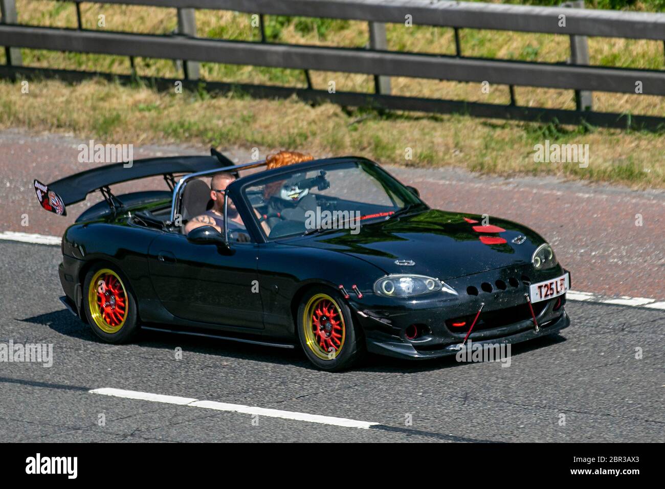 2013 black Mazda Mx-5 1.8i with mannequin propped up in the passenger seat;  Custom, rare lifestyle, modified, personalization, unusual personalised motors, modding, bespoke. Vehicular traffic moving vehicles, driving vehicle on UK roads, motors, motoring on the M6 motorway highway Stock Photo