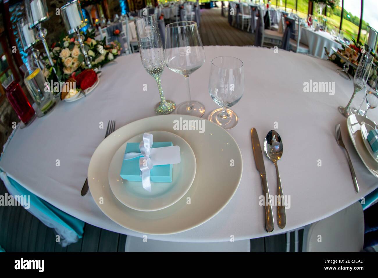 Table setting with handmade gift box on plate, glasses, forks, spoons ...