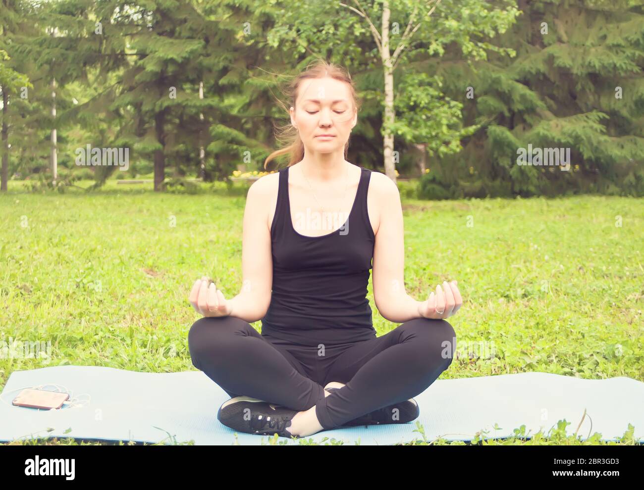 Attractive young woman exercising and sitting in yoga lotus position in ...