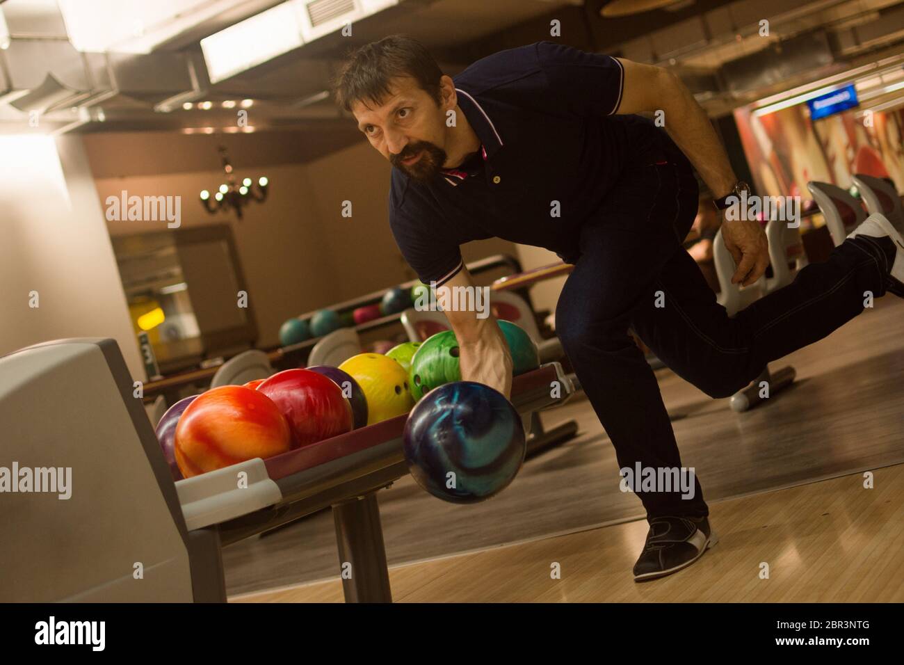 The male player is playing bowling in the bowling club. Stock Photo