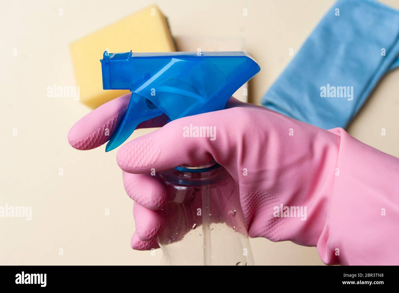 hand in rubber glove holding spray with detergent for cleaning house ...