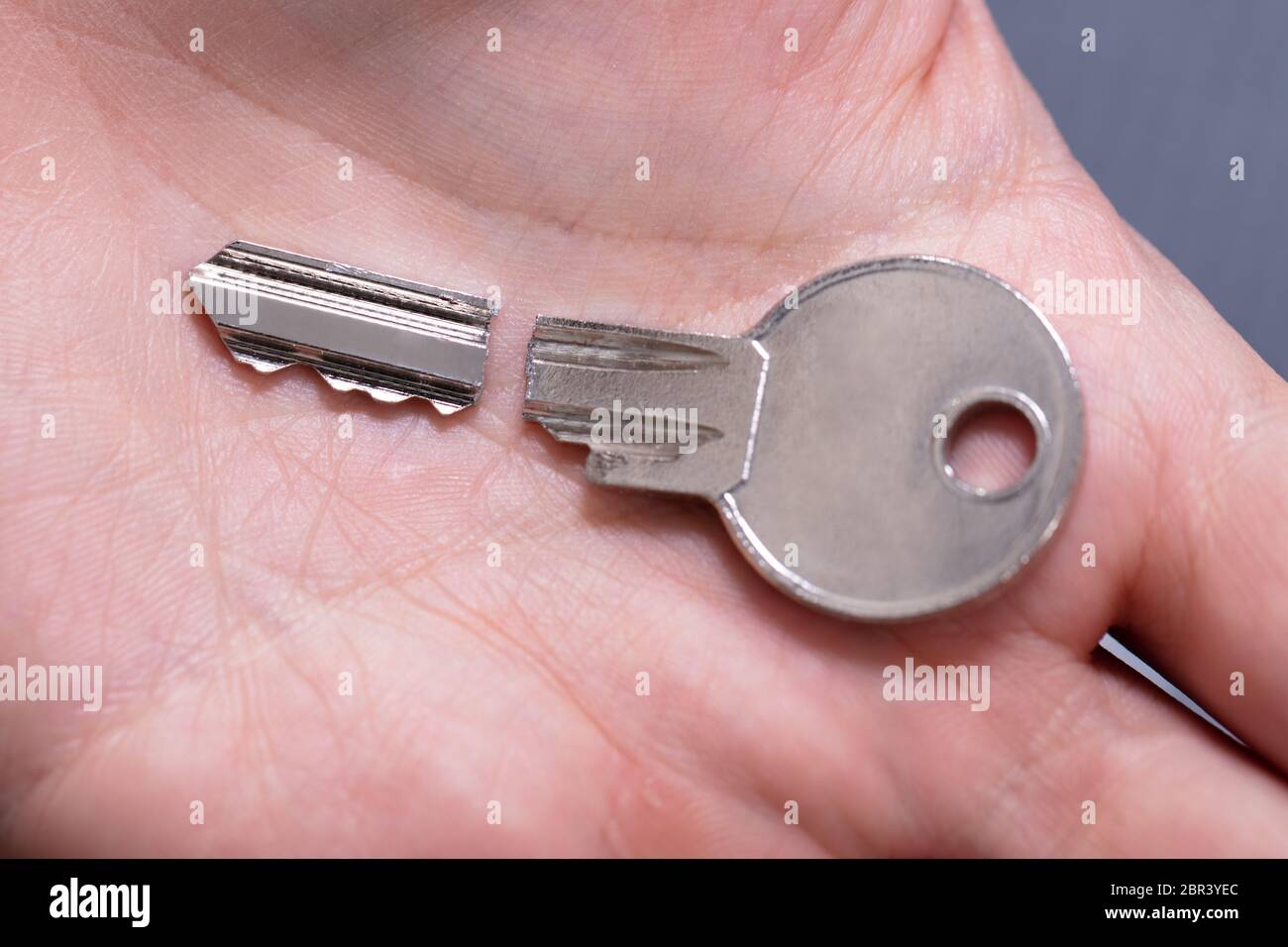 Close-up Of Person's Hand Holding Silver Broken Key Stock Photo