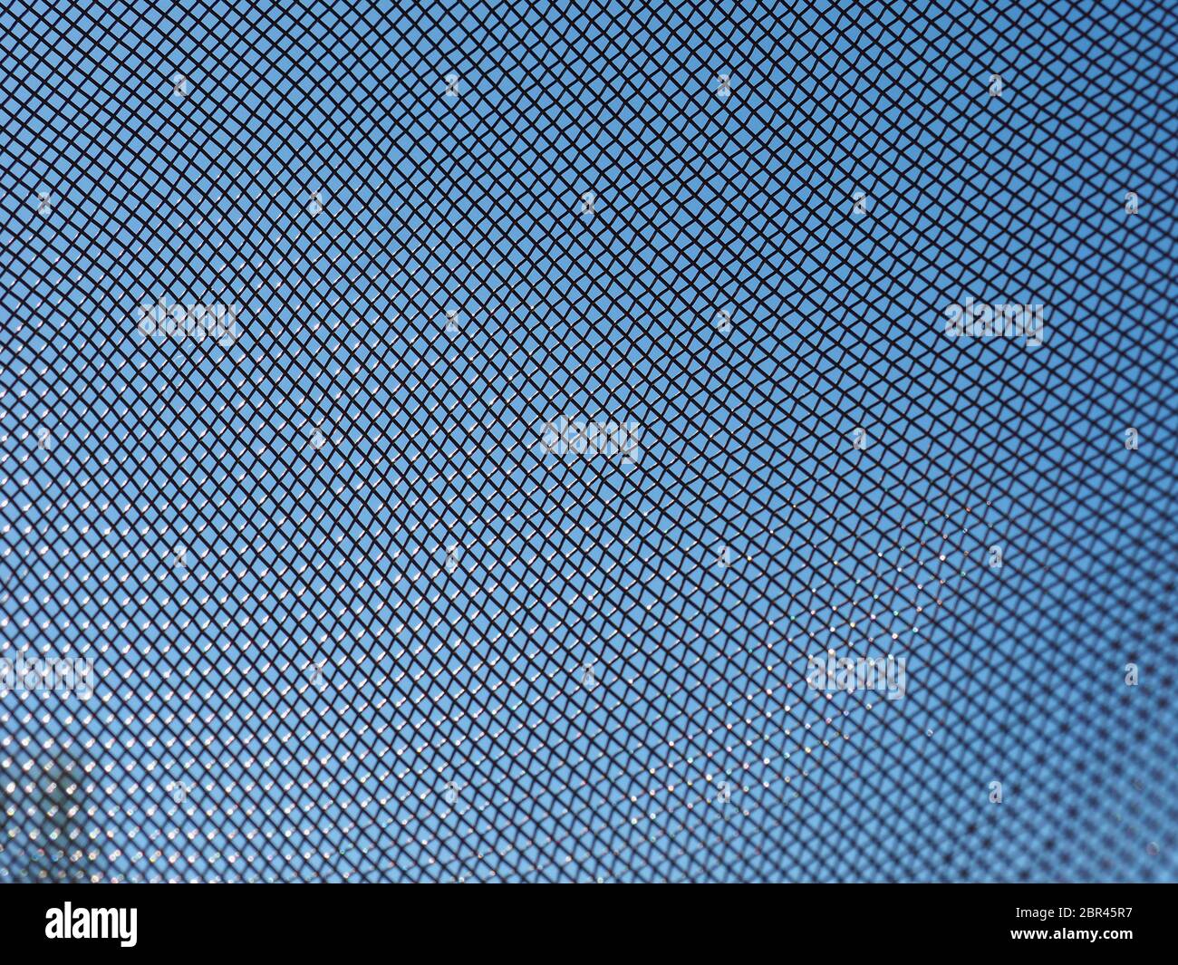 steel mesh texture over blue sky useful as a background Stock Photo