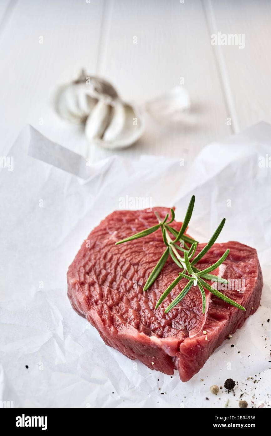 Raw portion of tender lean beef fillet steak topped with aromatic rosemary and seasoned with