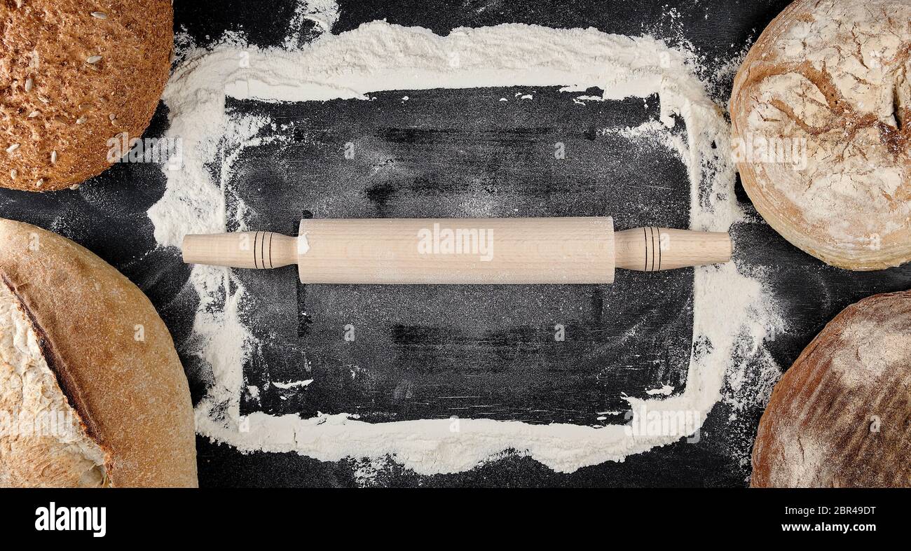 baked various loaves of bread and rolling pin on a black background ...