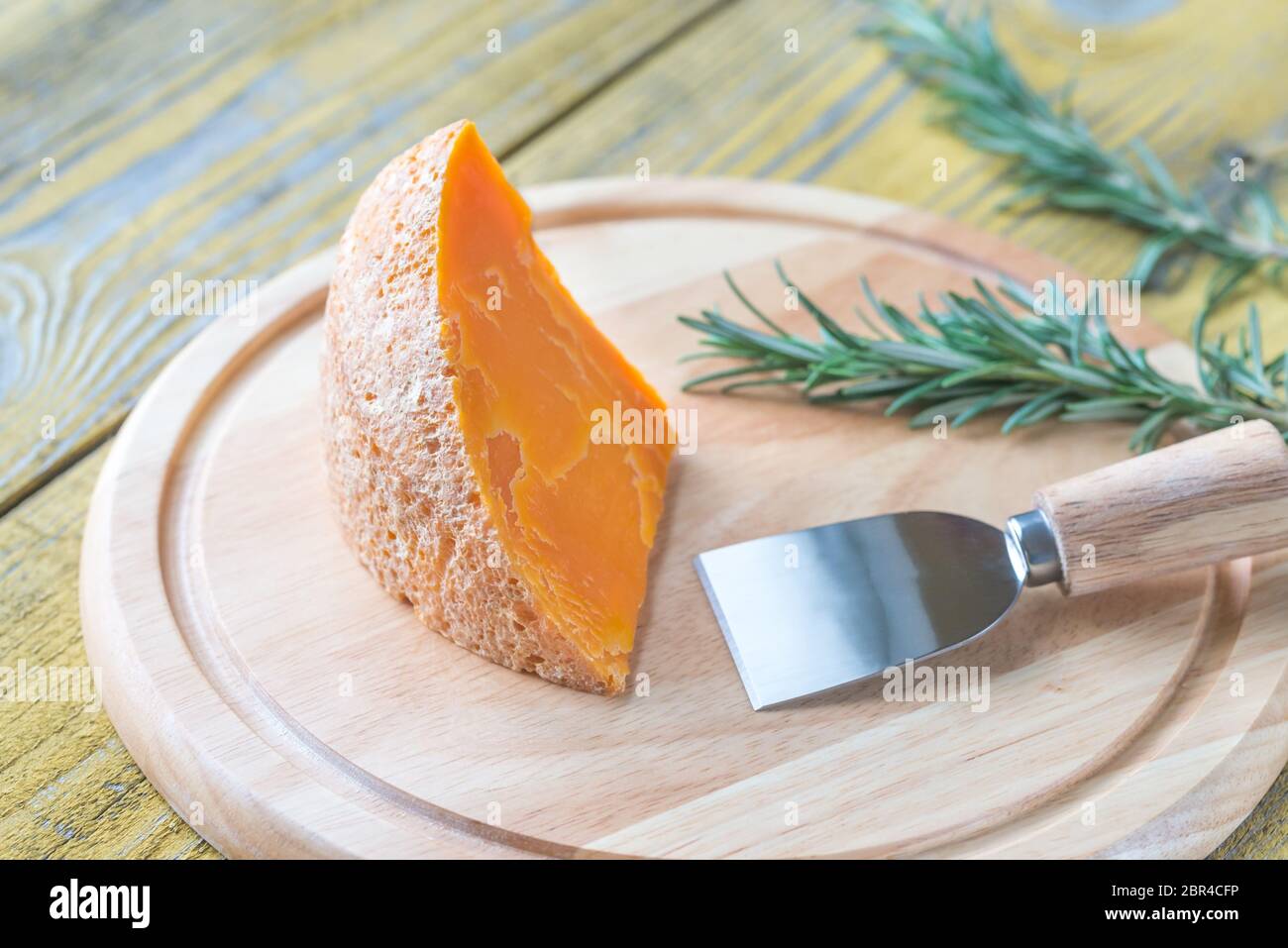 Wedge of Mimolette cheese on the wooden board Stock Photo