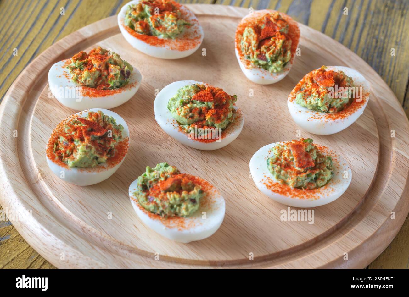Guacamole and bacon deviled eggs on cutting board Stock Photo