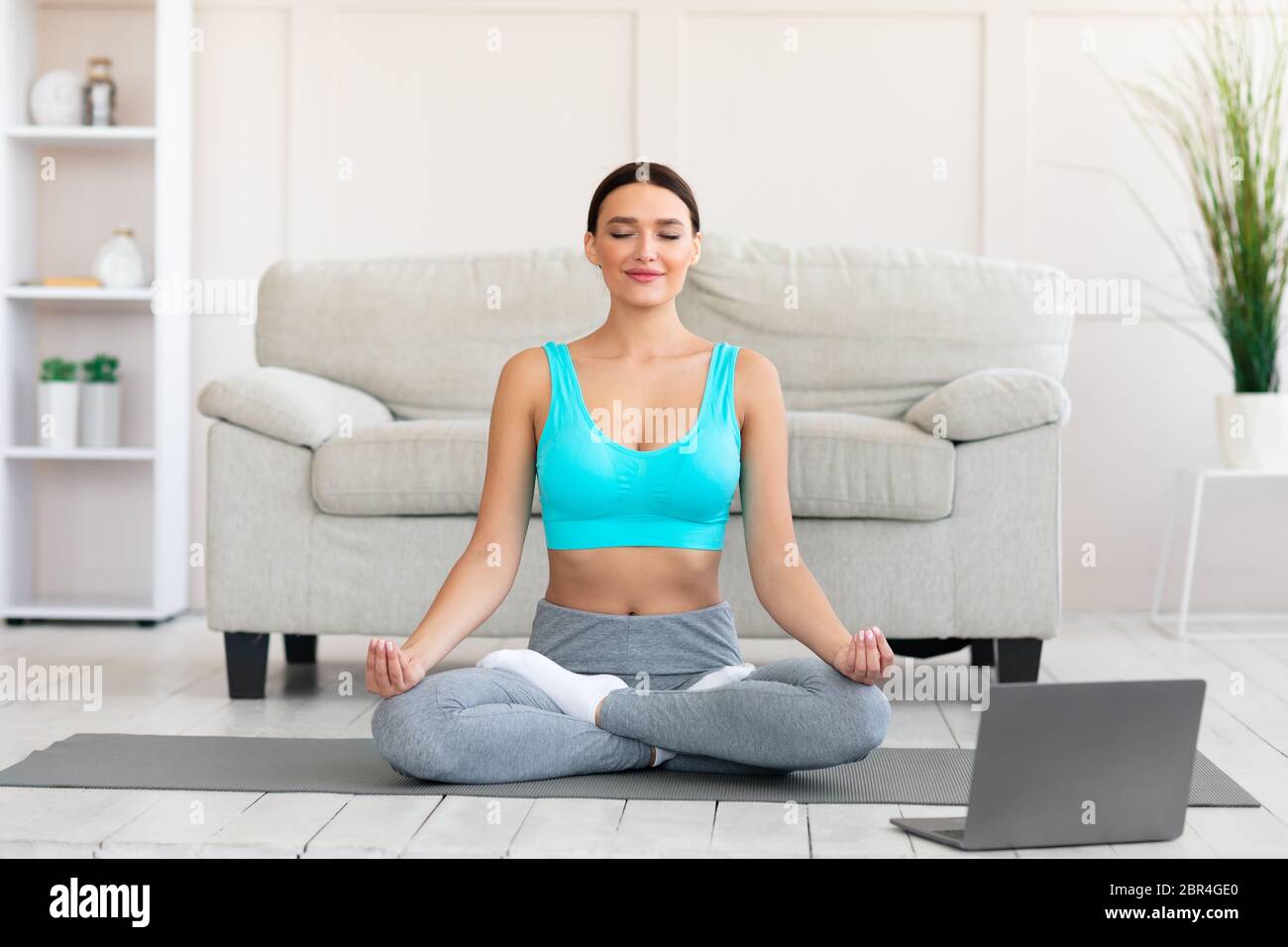 Girl Meditating At Laptop Sitting In Lotus Position At Home Stock Photo ...