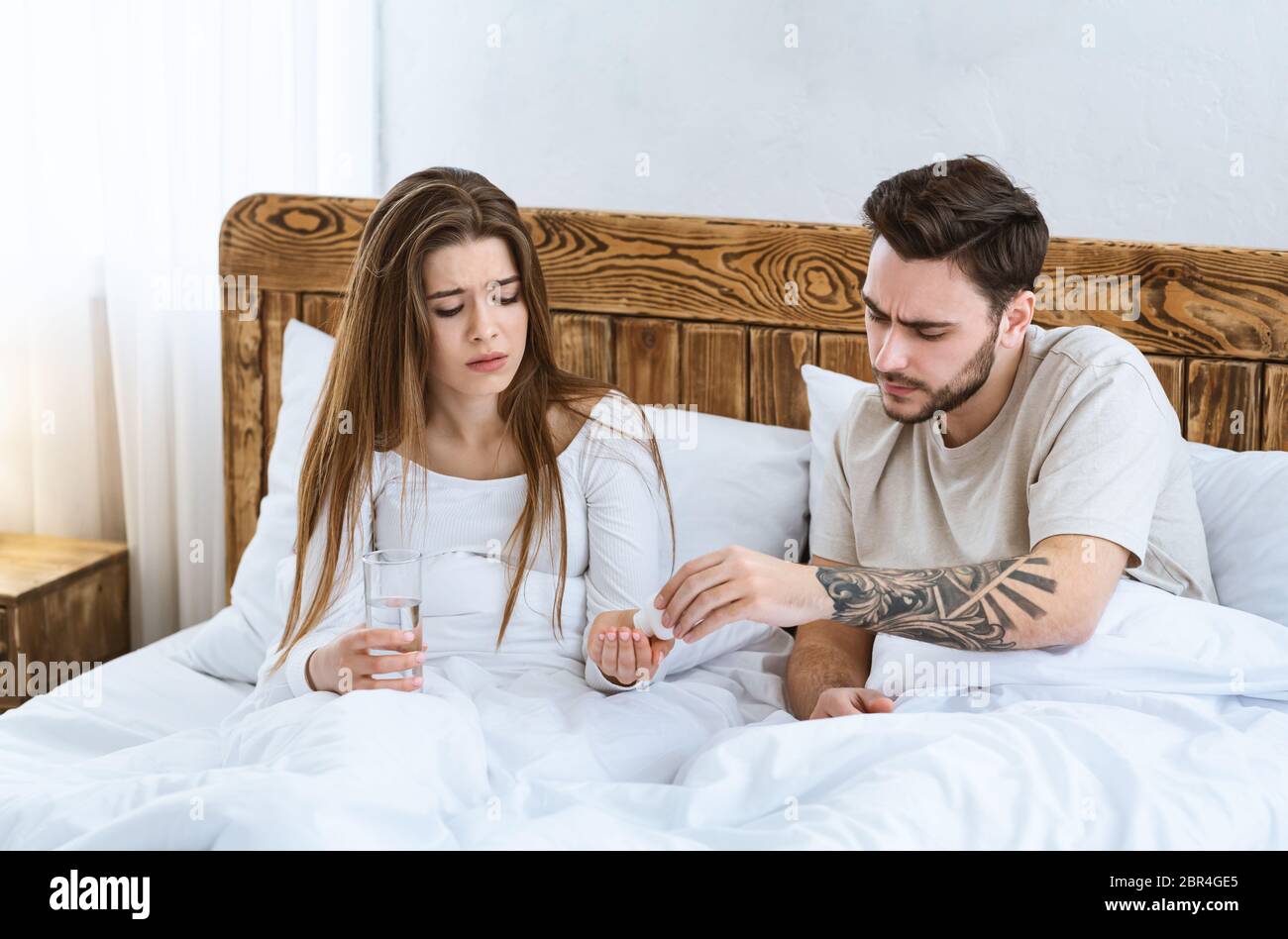 Home treatment. Sad man and woman are sitting in bed Stock Photo
