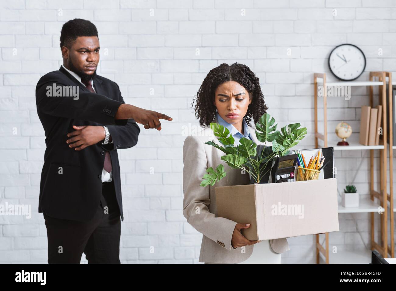 Crisis and unemployment. Cruel African American boss dismissing his sad female employee from company office Stock Photo