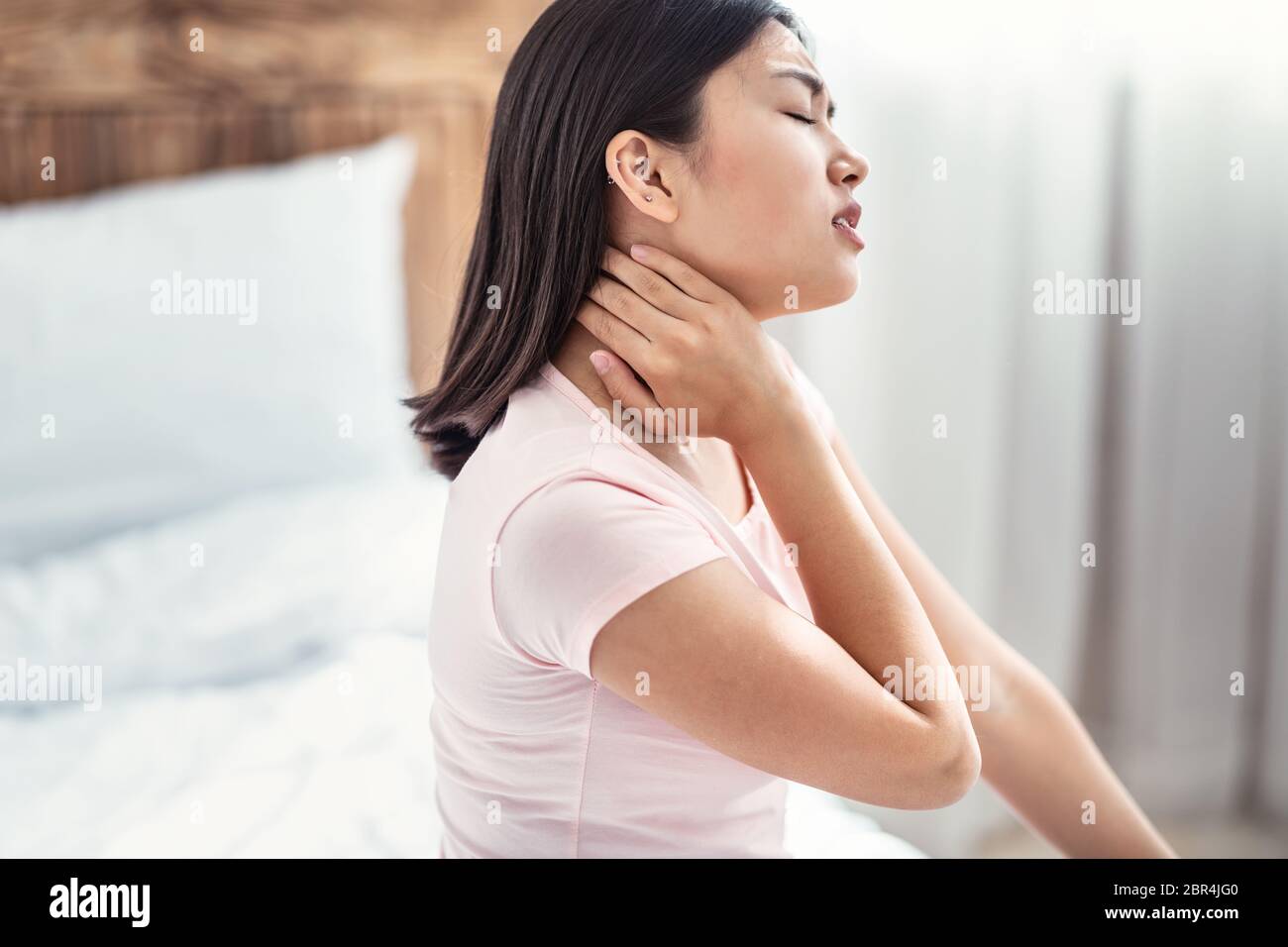 Korean Woman Having Neck Pain Sitting In Bed At Home Stock Photo