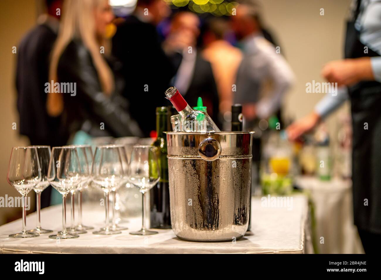 Bucket with ice, wine bottles and empty glasses on table in restaurant. Ice bucket, wine glasses and bottles arranged on the table for wedding recepti Stock Photo
