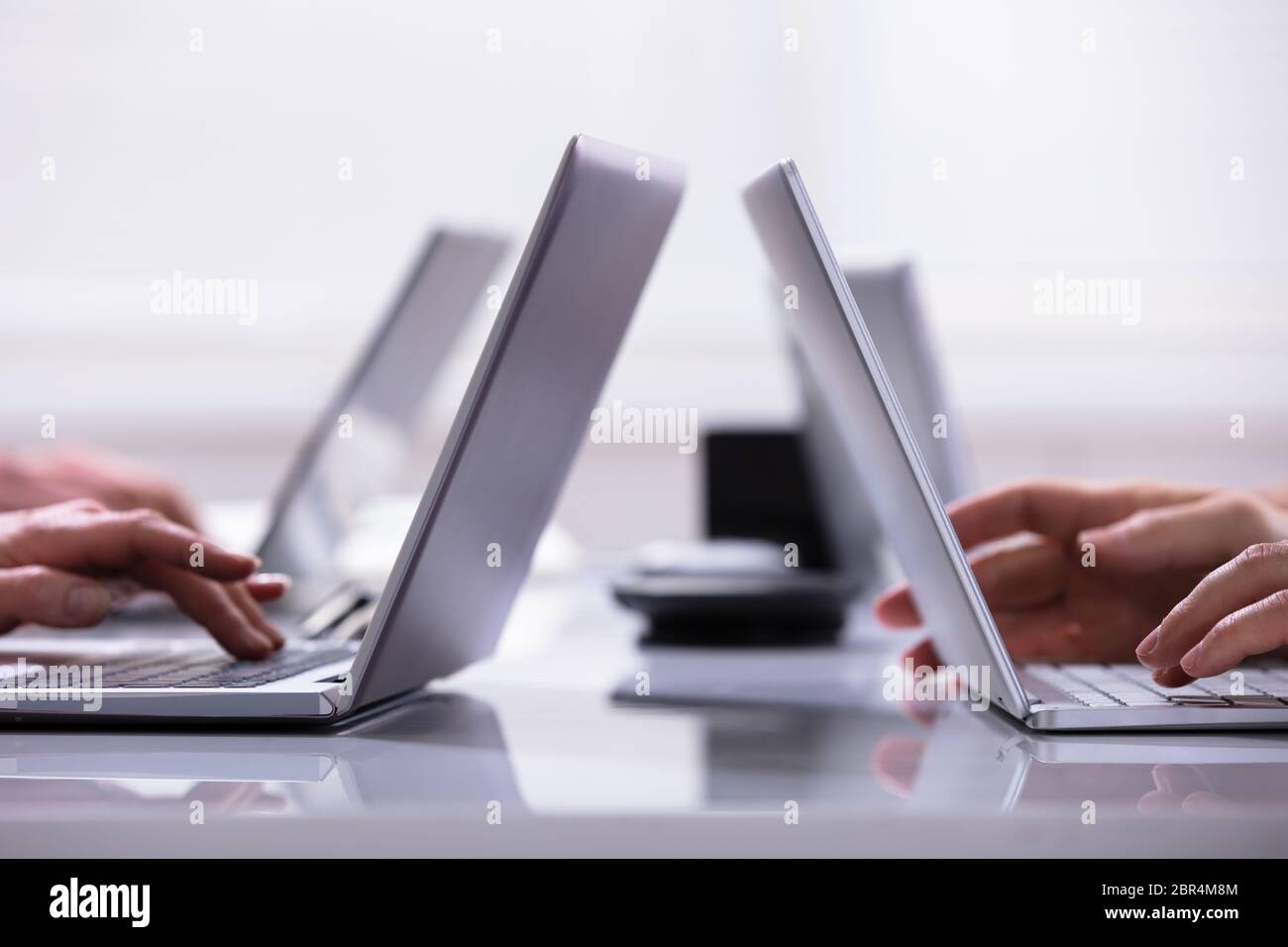 Close-up Of A Businessman Hands On Laptops Keypads On Desk In Office Stock Photo