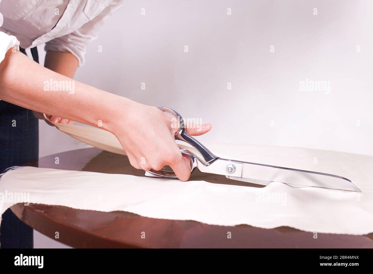 Seamstress cuts fabric with tailor's scissors Stock Photo Alamy