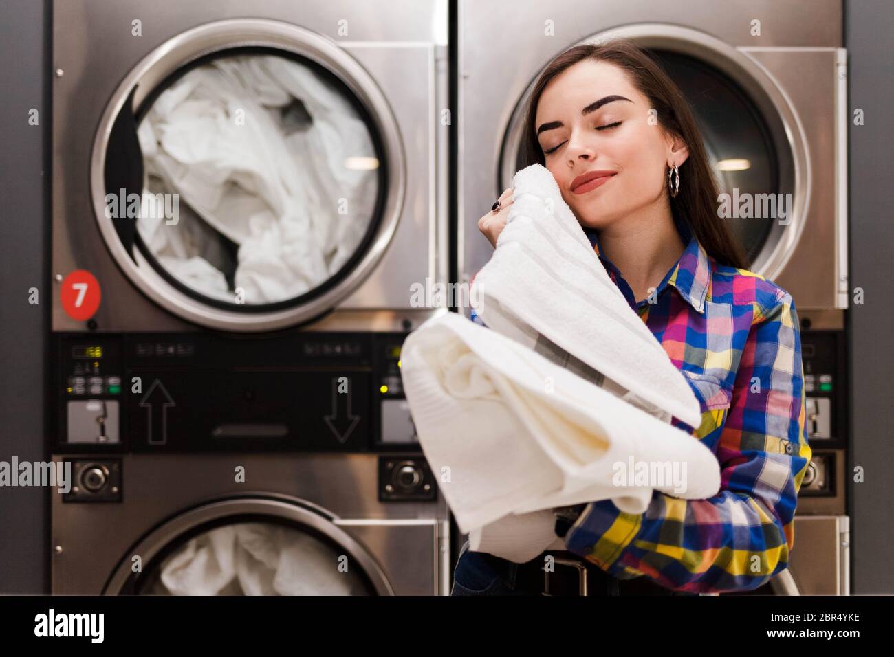 Girl enjoys clean and smelling towels after washing in launderette ...