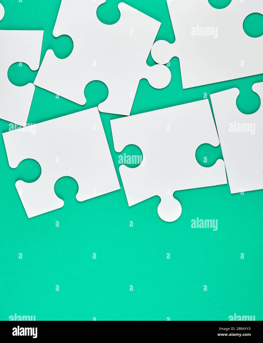 blank white big puzzles on green background, copy space Stock Photo