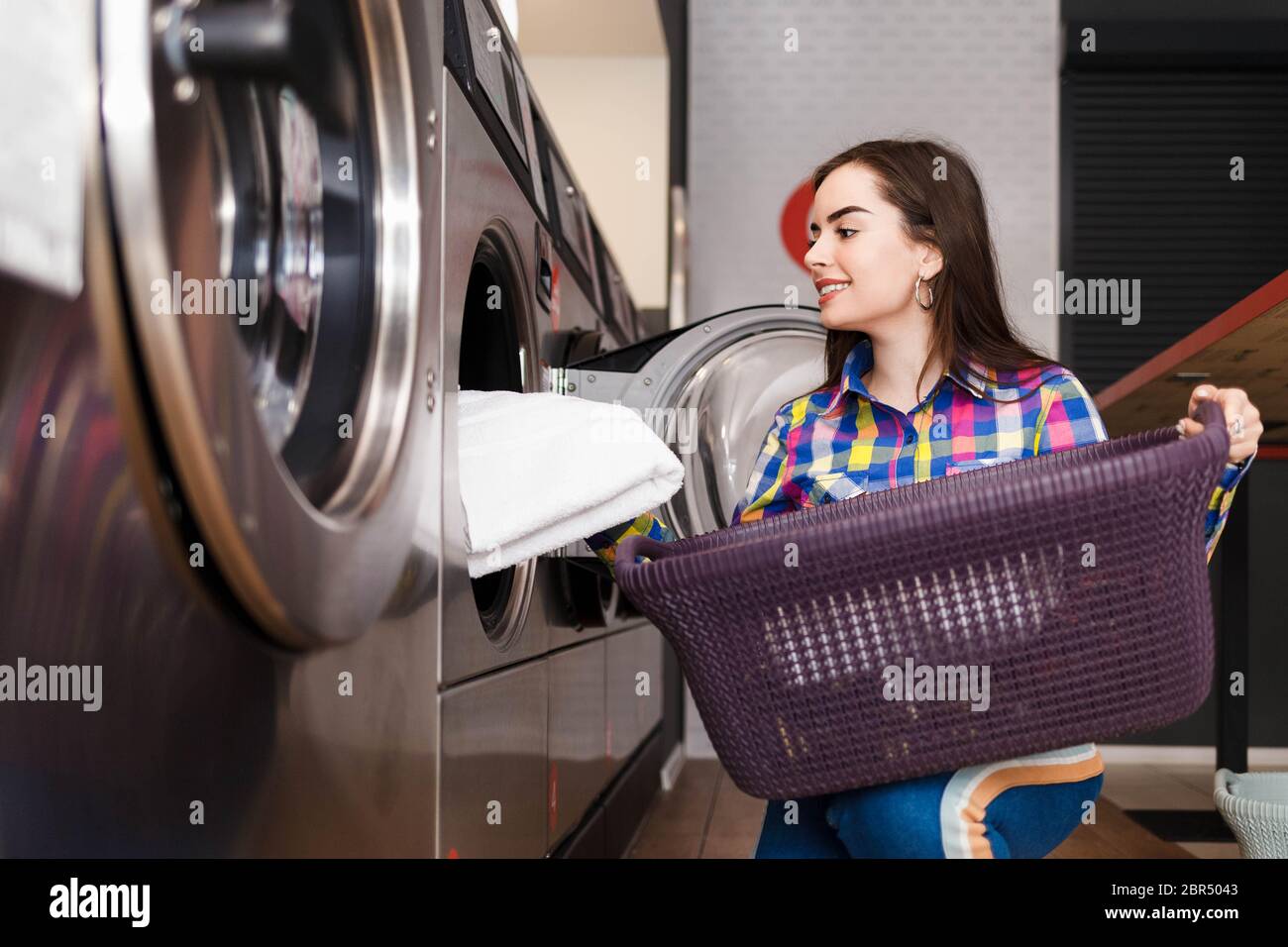 Girl loads laundry into a washing machine. woman in laundrette Stock Photo