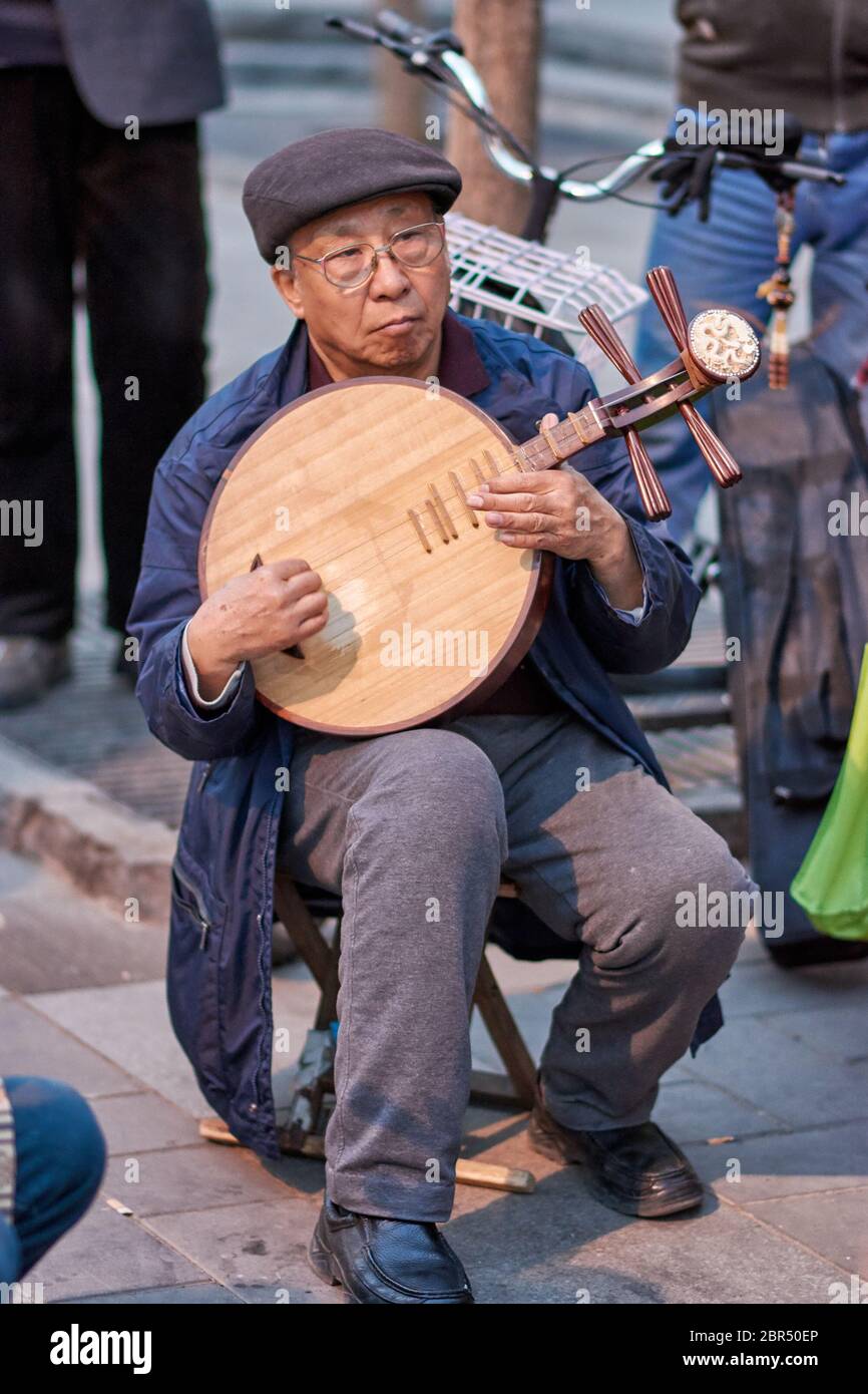 Beijing / China - April 9, 2016: Elderly man playing traditional Chinese instrument in a park in Beijing, China Stock Photo