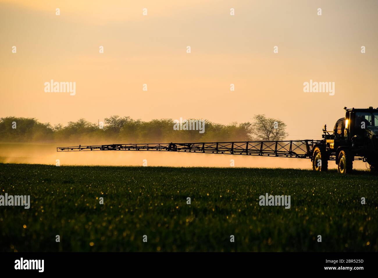 Jets of liquid fertilizer from the tractor sprayer. Tractor with the