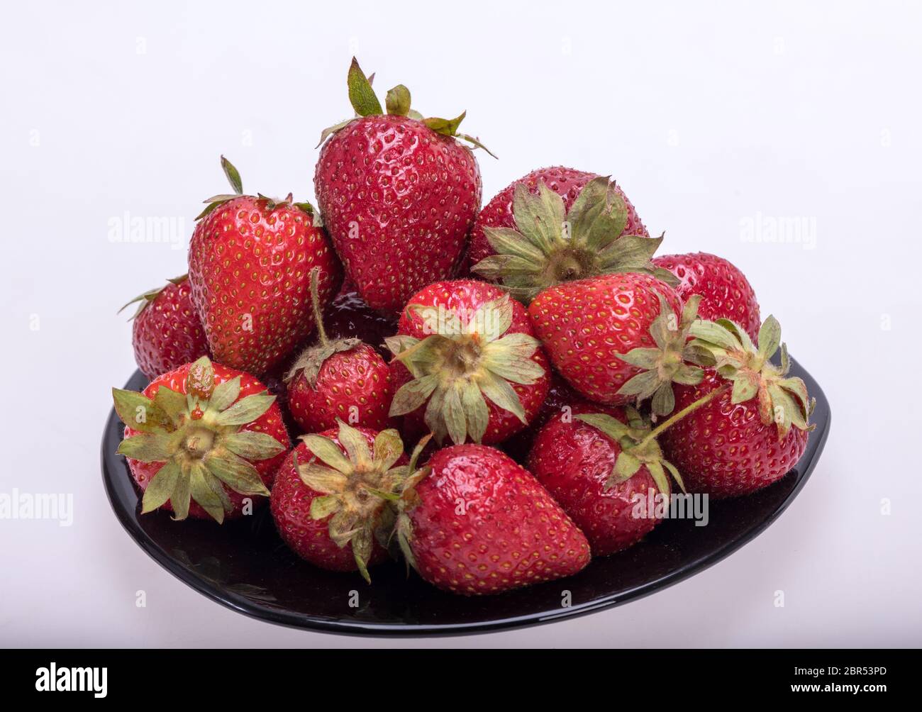 fresh ripe strawberries on black plate isolated on white background ...