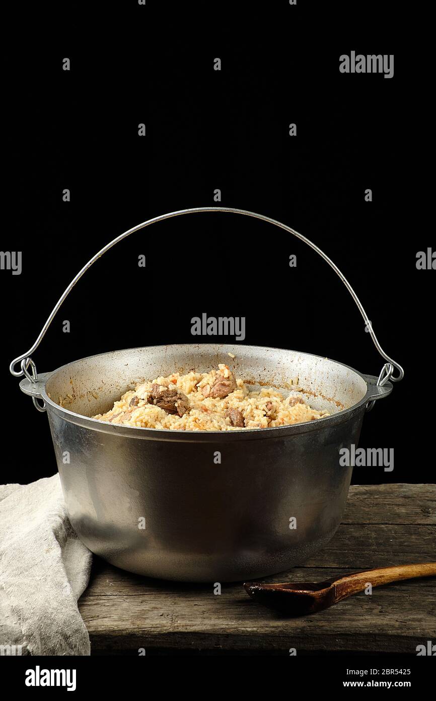 https://c8.alamy.com/comp/2BR5425/pilaf-is-an-oriental-dish-of-boiled-rice-with-fat-and-slices-of-meat-and-spices-the-dish-is-cooked-in-a-large-aluminum-cauldron-black-background-2BR5425.jpg