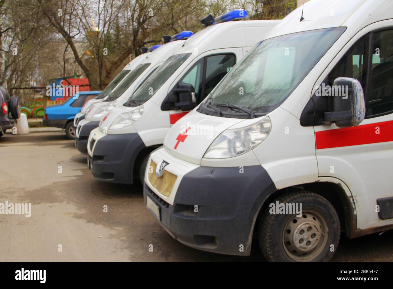 White ambulance with a red stripe with blue flashing lights on a city street in Russia. Stock Photo