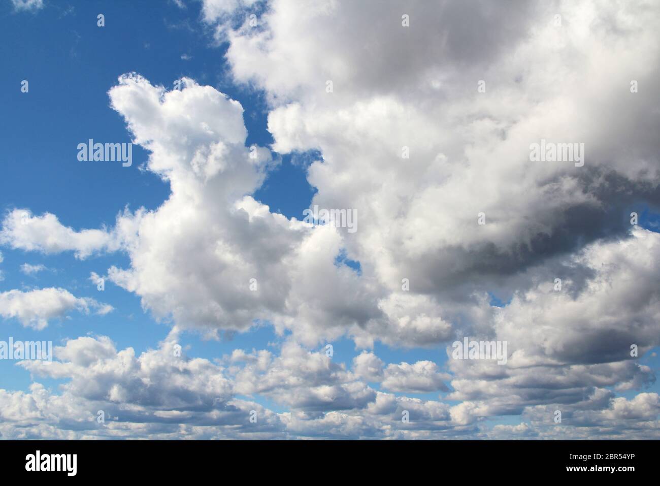 White fluffy clouds on a background of blue sky in summer. The concept of weather and climate. Stock Photo