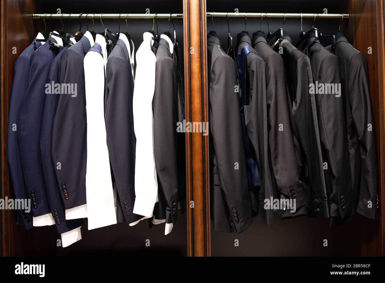 Many men's suits on a hanger in the store Stock Photo