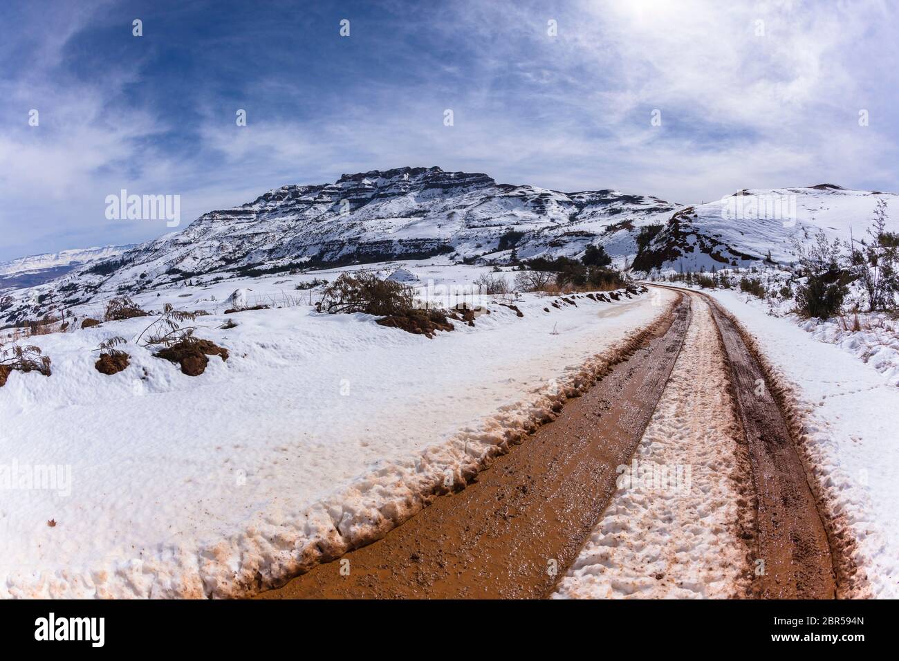 Mountains Snow dirt road tracks towards hilltop Stock Photo