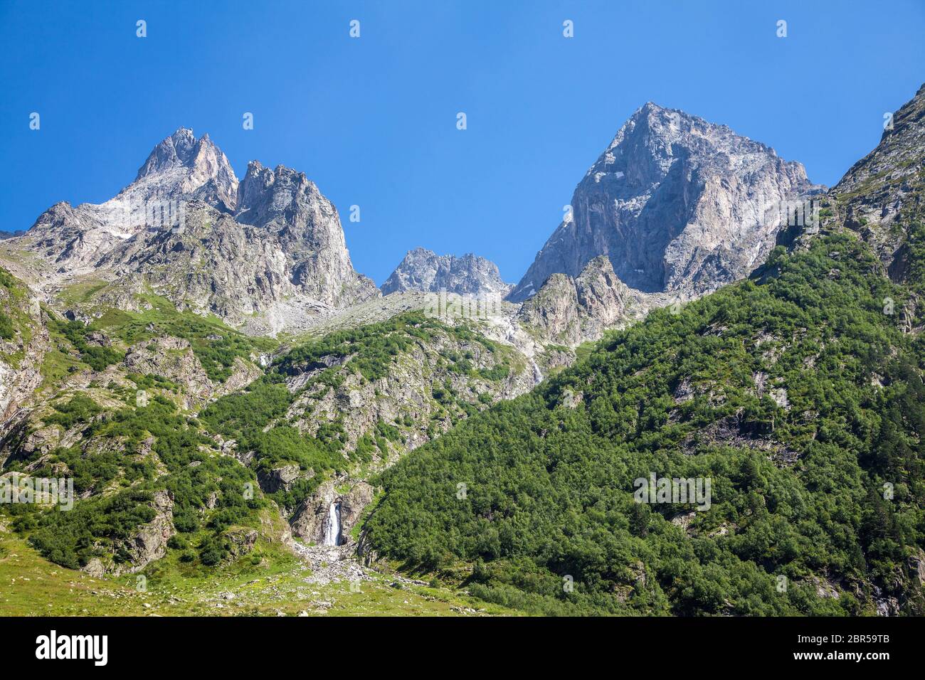 Mountain landscape with a waterfall, forest and blue sky. Copy space ...