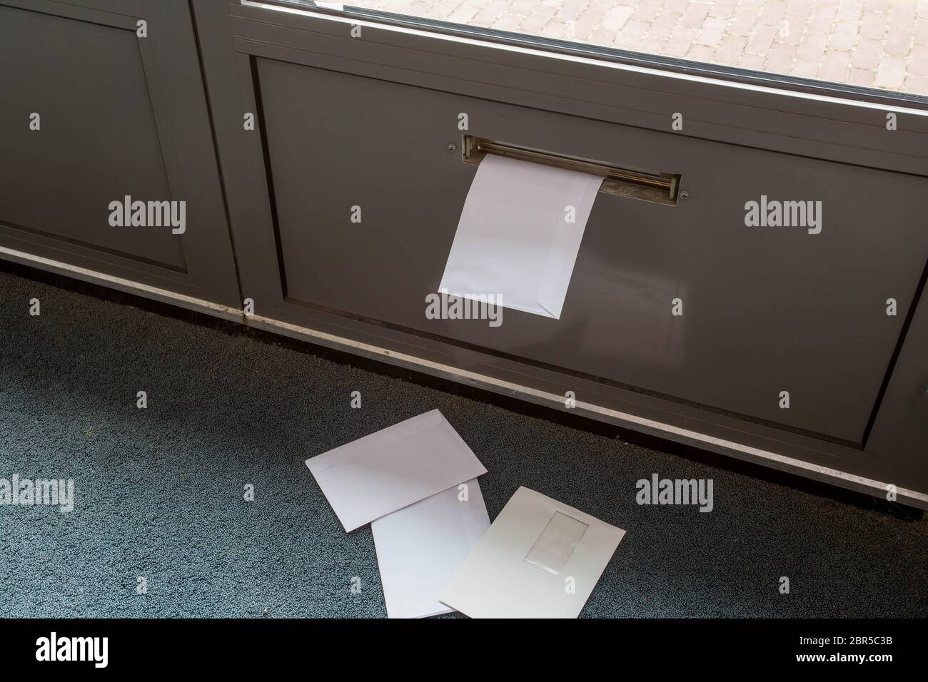 Post lying on the floor and in the door mailbox in a empty building close-up Stock Photo