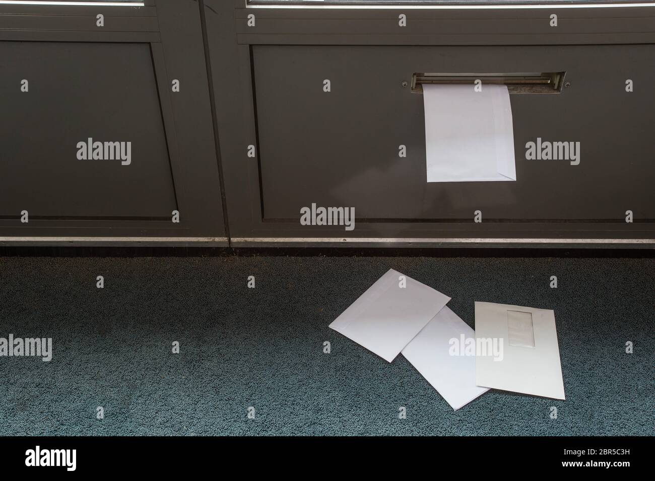 Post lying on the floor and in the door mailbox in a empty building close-up Stock Photo