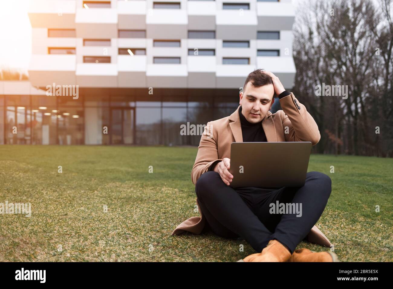 Man hold his head while working on a laptop Stock Photo