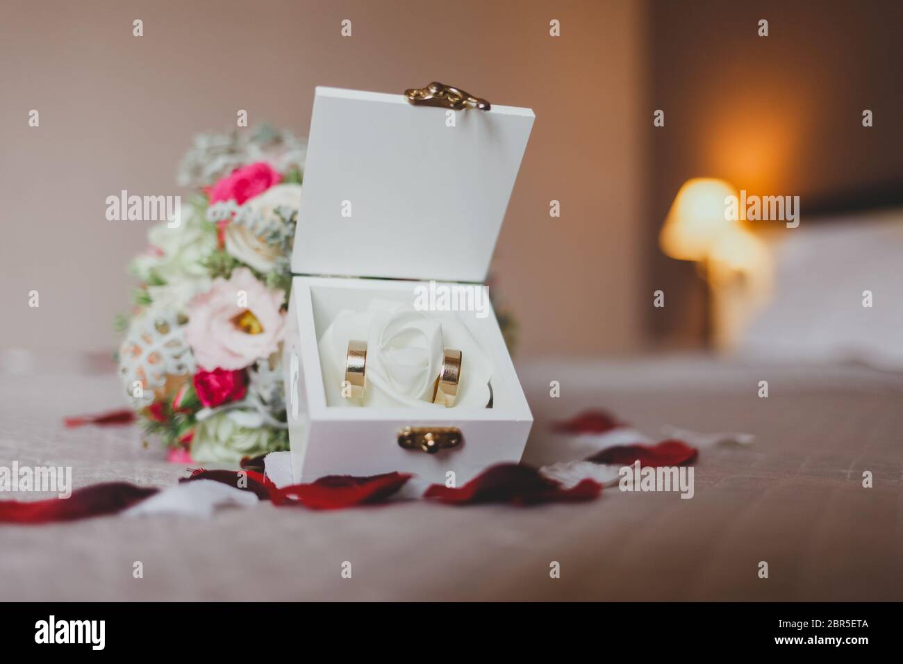 Bouquet and box with wedding rings in a bed strewn with rose petals Stock Photo