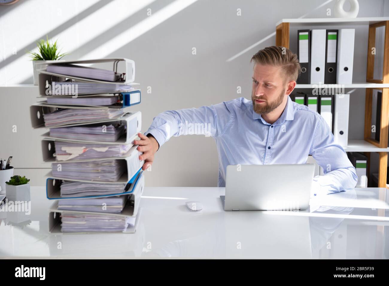 Businessperson Pushing Paper Documents Away And Working With Digital Documents On Computer Instead Stock Photo