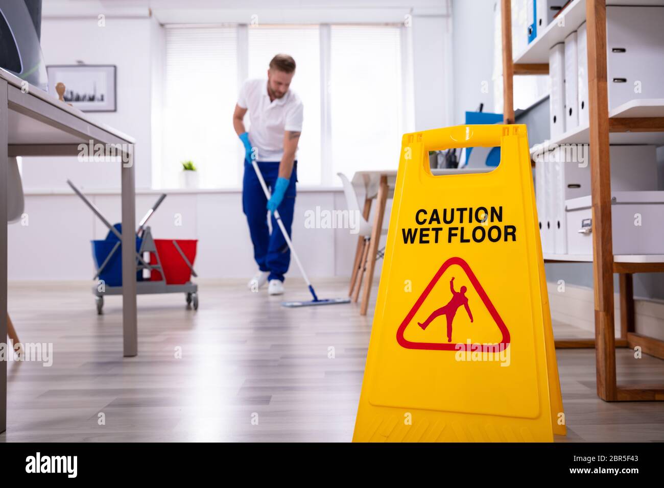 Male janitor with mop cleaning modern office floor Stock Photo