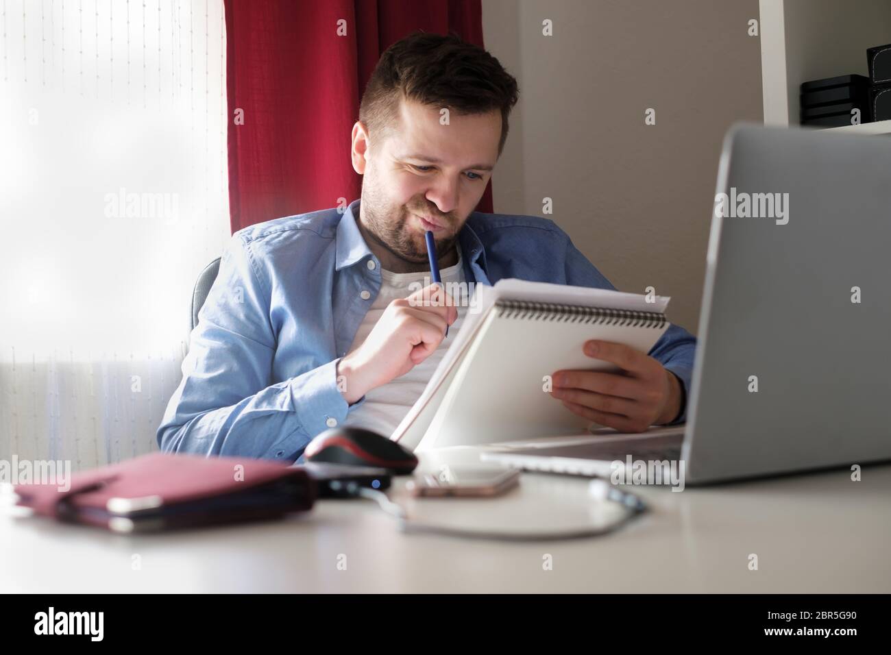 Young caucasian man working from home reading documents during isolation Stock Photo